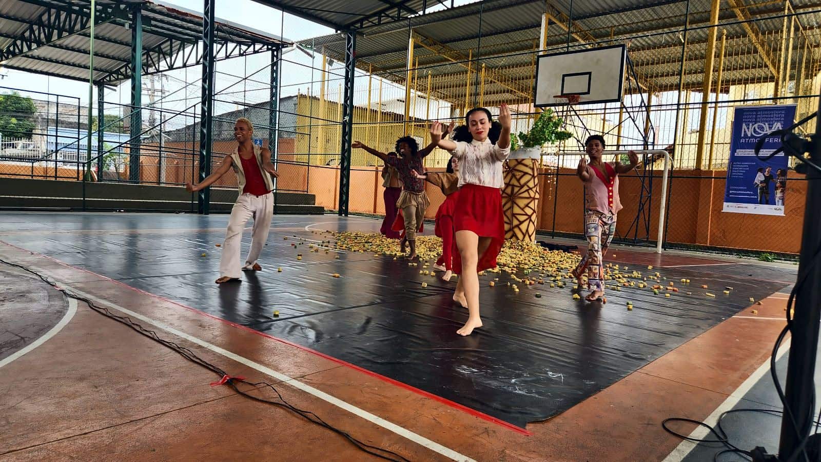 Bailarinos dançam o Pé de Cachimbo sobre a lona preta, na quadra coberta de uma escola municipal