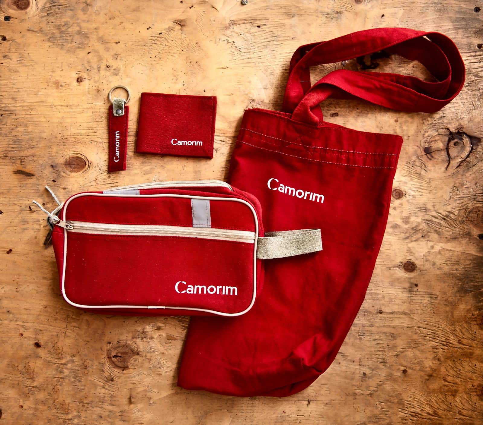Necessaire, ecobag, carteira e chaveiro vermelhos com a marca Camorim, feitos de macacões reaproveitados