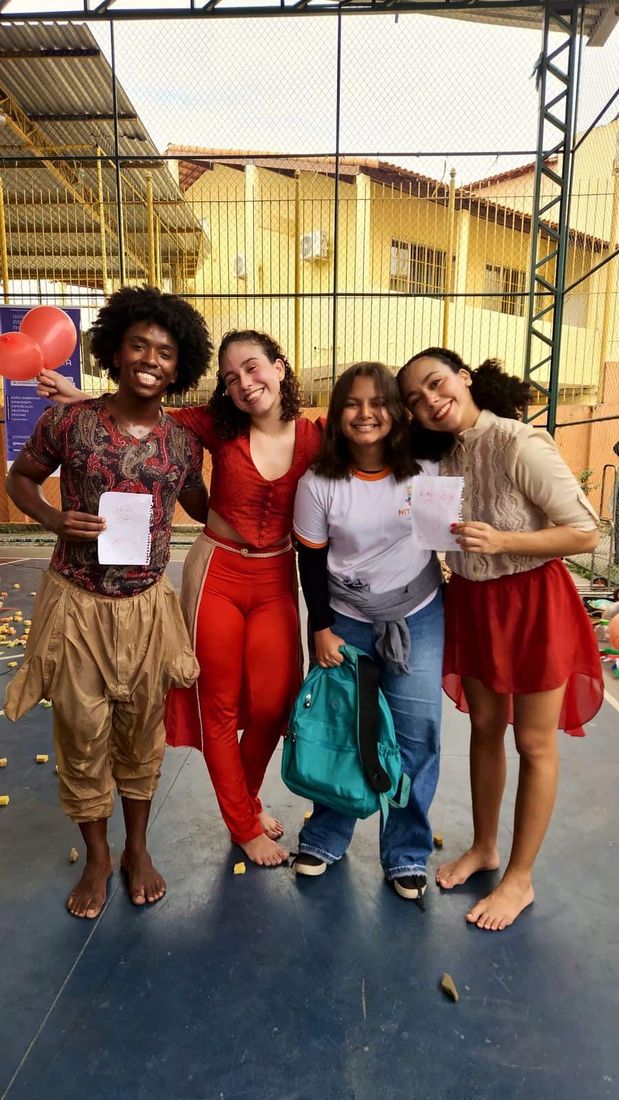 Bailarinos do Pé de Cachimbo, de figurino, posam abraçados com alunas na quadra da escola