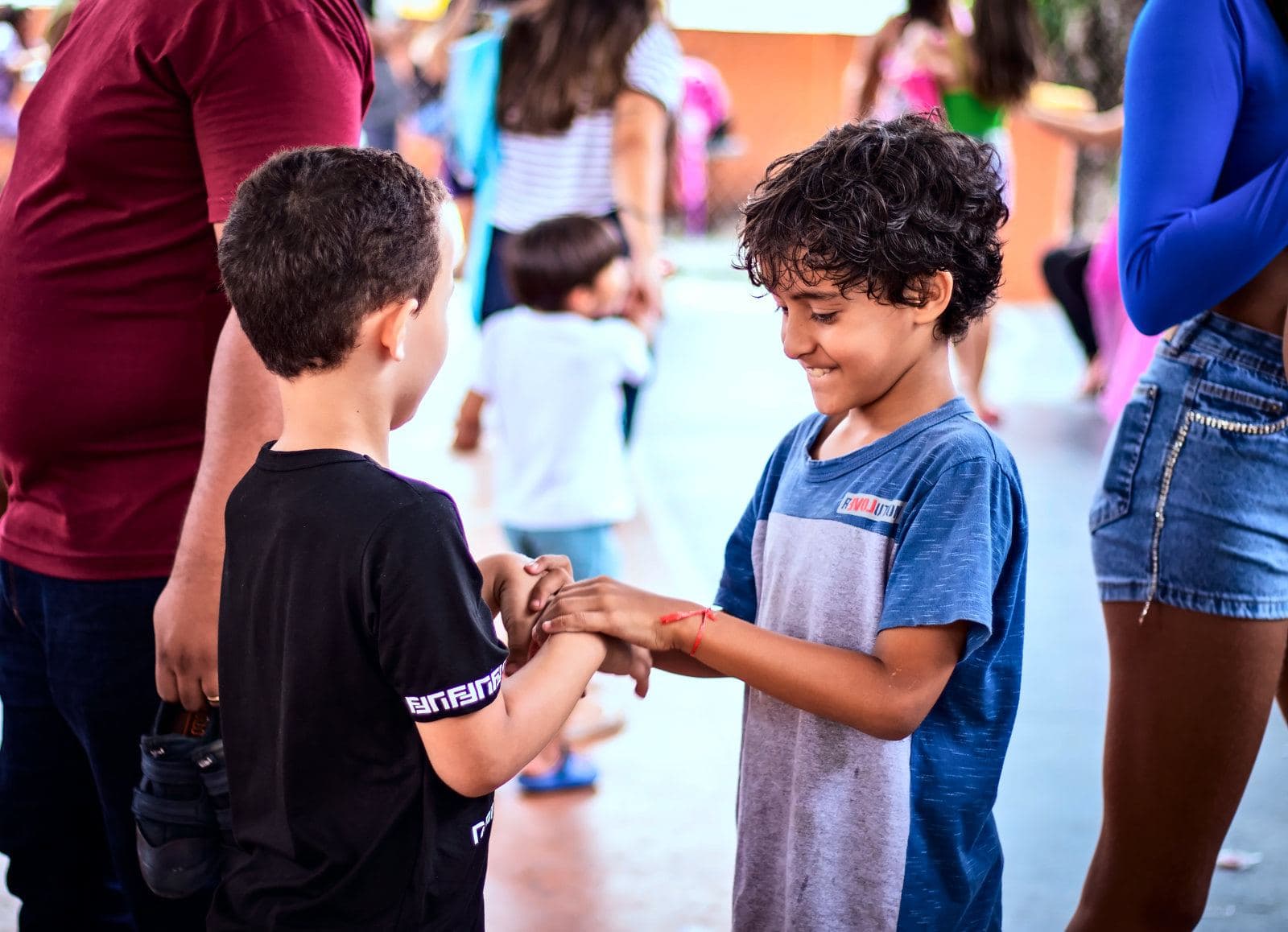 Dois meninos se cumprimentam sorrindo no meio da festa